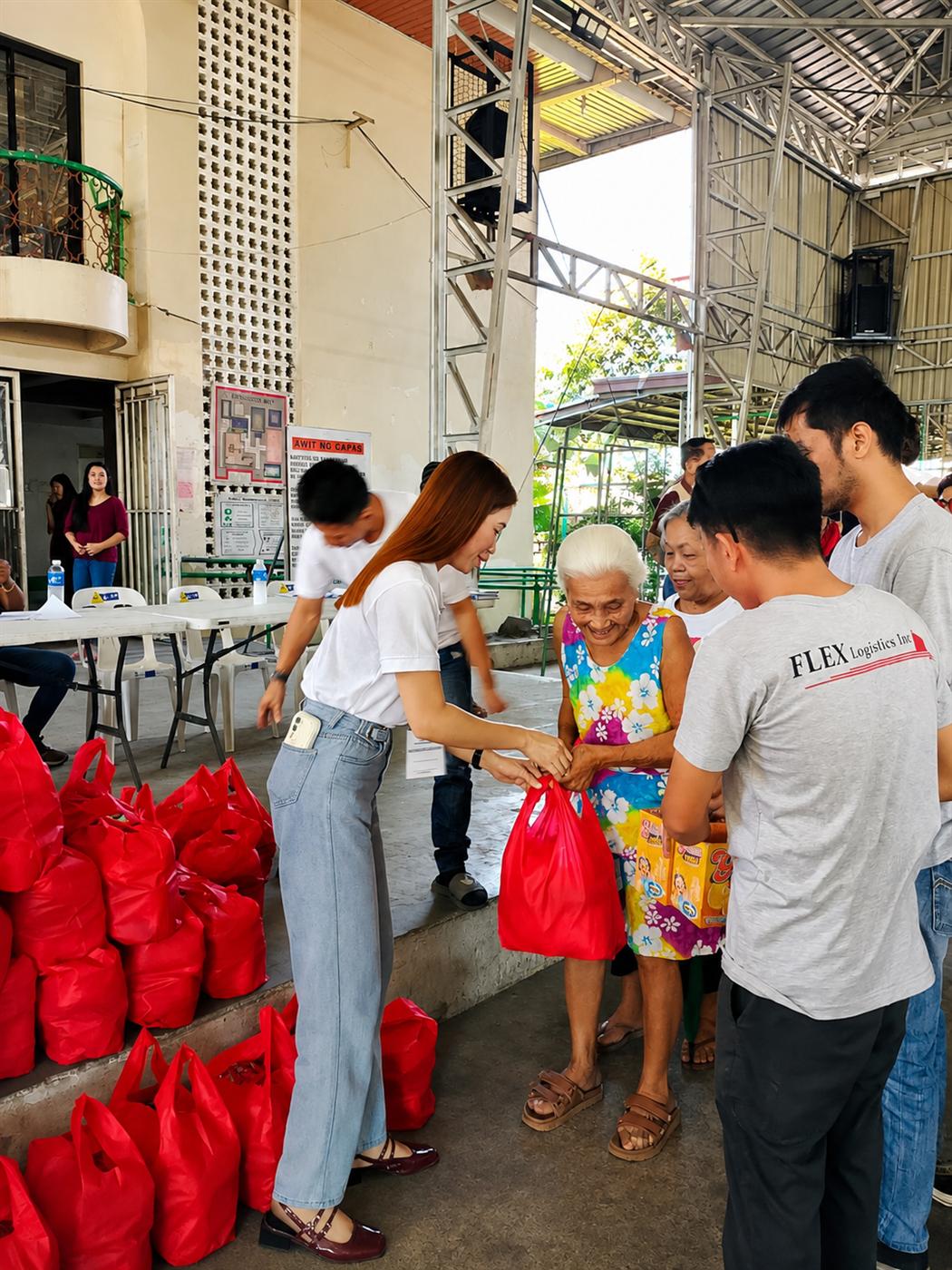 A Flex Logistics Inc. team member handing a food pack directly to a resident