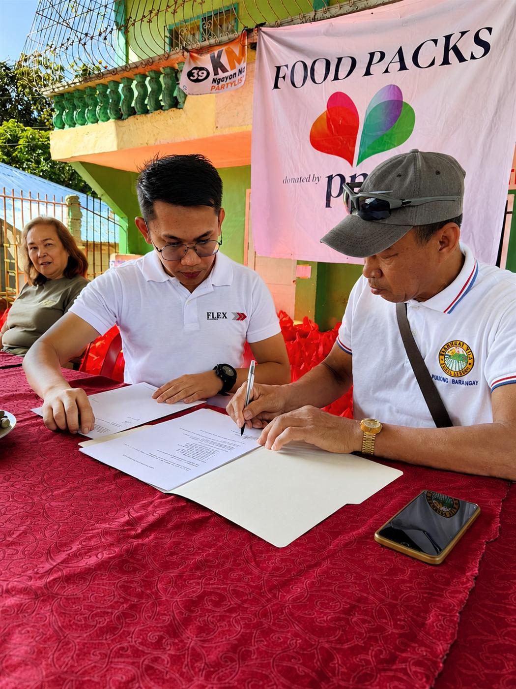 A Flex team member signing off with barangay leadership